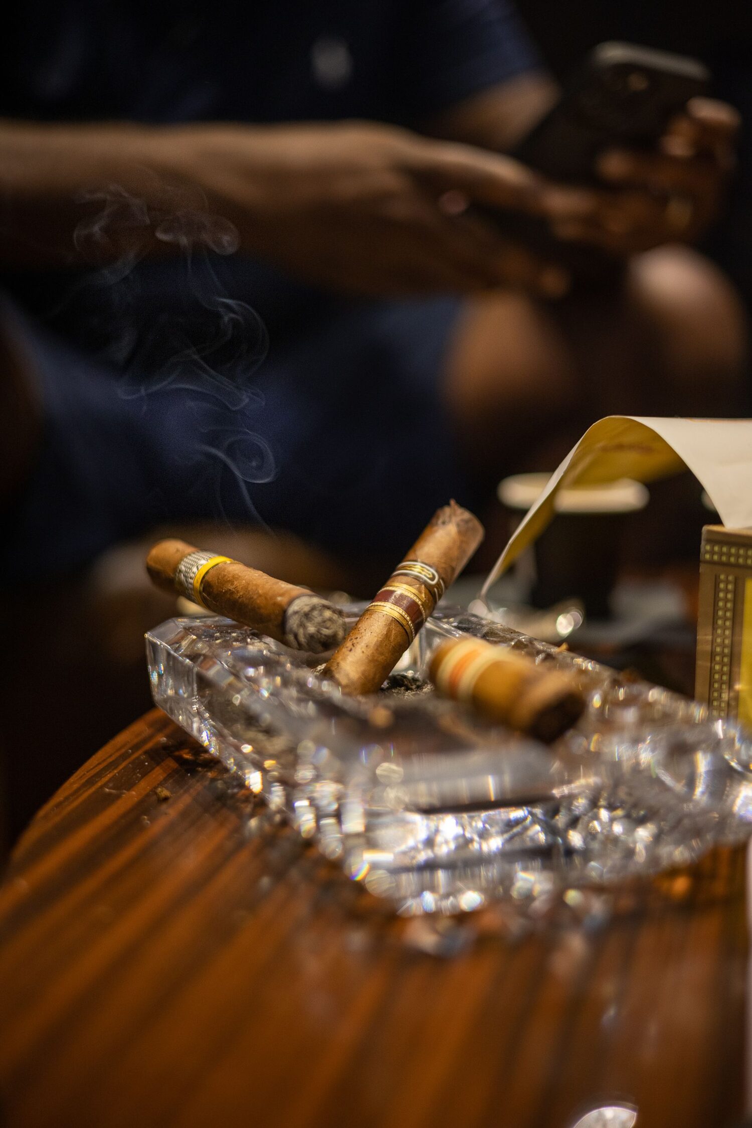 Cigars resting in a crystal ashtray in a dim members lounge
